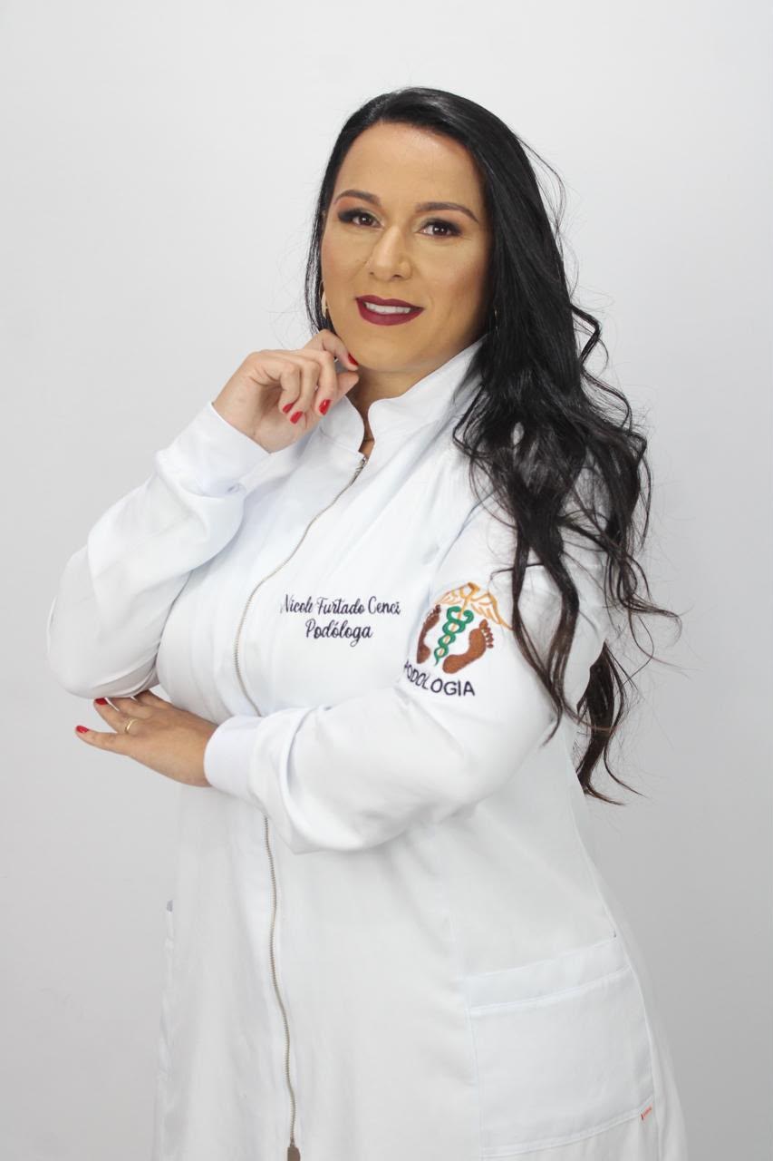 Nicole Cenci de jaleco branco bordado com o nome dela e a palavra Podóloga